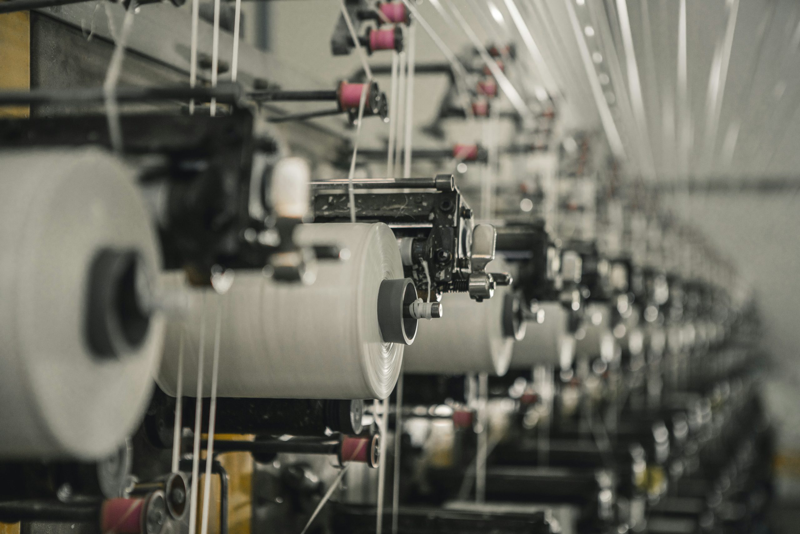 Textile manufacturing machinery with colorful spools of thread in a factory